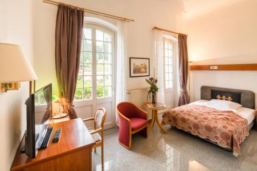 巴特嫩多夫伊斯帕拉德大酒店的一间卧室配有一张床、一台电视和一张书桌