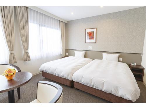 舞鹤市阿玛拜耳舞鹤酒店的酒店客房设有一张大床和一张桌子。