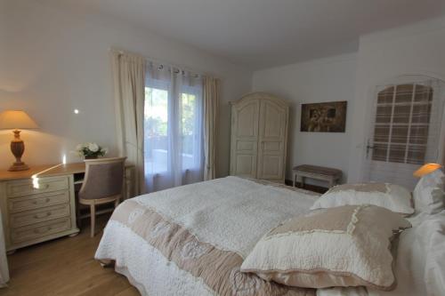 格拉斯Aux charmes de grasse的白色的卧室设有床、书桌和窗户