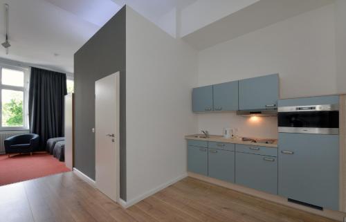 亚琛派克公寓的一间设有蓝色橱柜和一扇开放式门的厨房