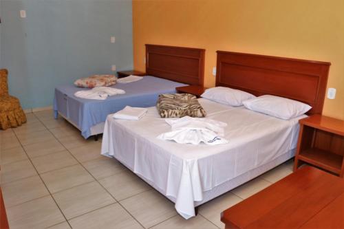 克拉鲁河畔卡尔穆Pousada Recanto das Águas的客房内的两张床,带一个钱包