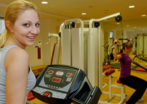 爱尔福特慕尼黑卡丽酒店的一名在健身房跑步机上跑步的女人