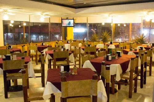 夸察夸尔科斯Hotel Enriquez的一间带桌椅和电视的用餐室