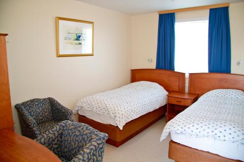 沃加尔沃加尔酒店的一间卧室设有两张床、一把椅子和一个窗户。