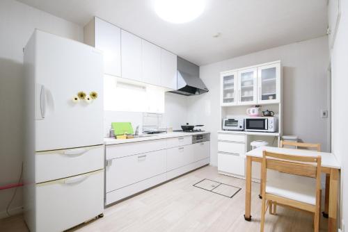 札幌HDO Sumikawa Villa的厨房配有白色橱柜、桌子和冰箱。