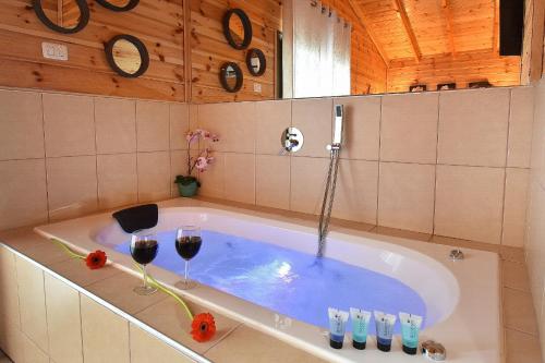 提比里亚אחוזת חוף כנרת kinneret village的一间带浴缸及两杯葡萄酒的浴室