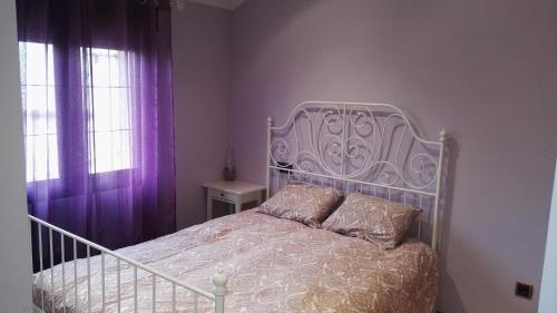 Otero de HerrerosCasa El balcón de Iria的卧室配有白色床和紫色窗帘