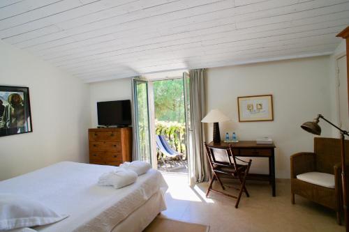 圣特罗佩Campagne les Jumeaux的一间卧室配有一张床、一张书桌和一个窗户。