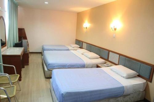 斗湖Monaco Dynasty Hotel的酒店客房设有三张床和一间浴室。