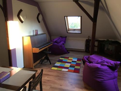 伦布尔克Apartman Adele的客厅配有钢琴和紫色枕头
