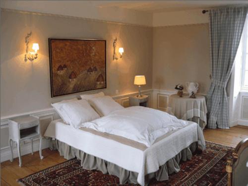 Sully小苏利商会酒店的卧室配有一张白色床,墙上挂有绘画作品