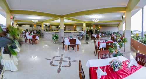 布琼布拉Tigers's apartment Hotel的餐厅配有白色桌椅和红色桌布