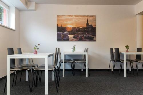 什切青City Rooms Szczecin的一间设有桌椅的房间和墙上的绘画