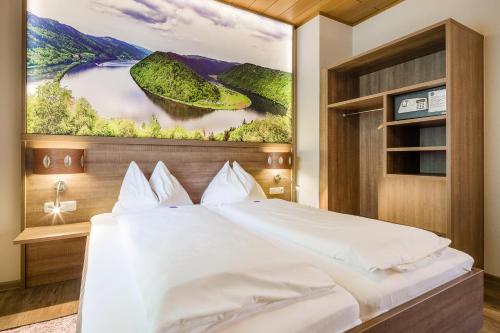 Obermühl吉尔林格酒店的卧室配有一张大床,墙上挂有绘画作品
