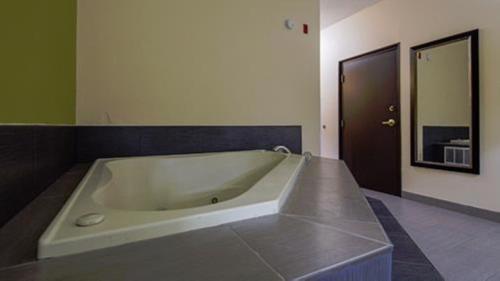 亨特斯维尔亨特斯维尔贝斯特韦斯特PLUS酒店的浴室设有绿色墙壁和大浴缸。