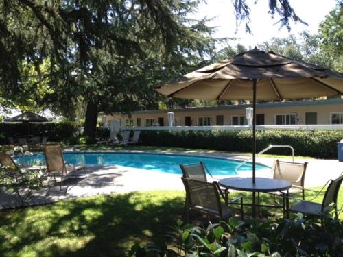 圣海伦娜艾尔波尼塔汽车旅馆的游泳池旁配有遮阳伞的桌椅