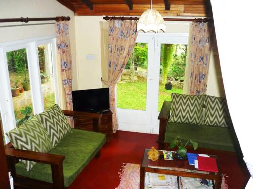 康提康提天堂小屋乡村民宿的客厅配有两张绿色沙发和一台电视机