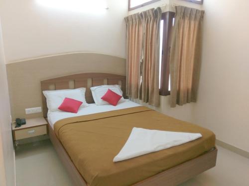 迈索尔Banyan Tree Comforts Mysore的一间卧室配有一张带两个红色枕头的床