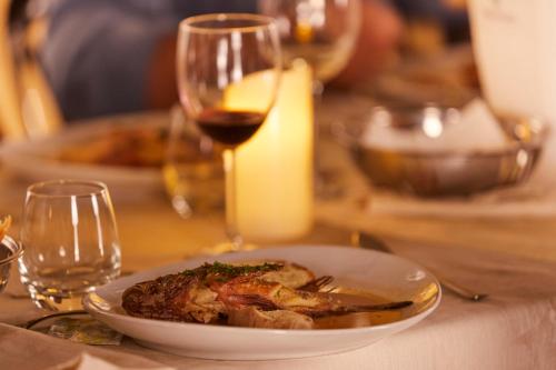 兰佩杜萨Alba D'Amore Hotel & Spa的桌上的一小块食物,加上一杯葡萄酒