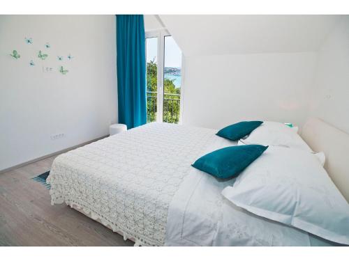 斯普利特豪华马里安公寓的一间卧室配有一张带蓝色枕头的床和一扇窗户。