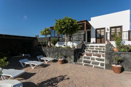 特吉塞Villa El Jable Lanzarote的一个带两个白色长椅的庭院和一座建筑