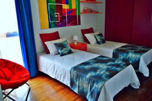 丰沙尔vista dos arrifes的一间设有两张床和红色椅子的房间