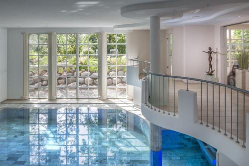 奥斯赛拜-塞林Romantik ROEWERS Privathotel & Spa的一个带楼梯的游泳池,铺有蓝色的瓷砖地板