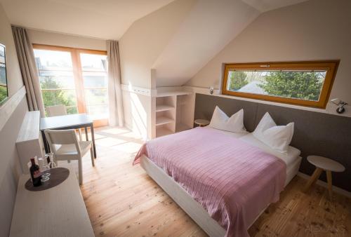 滨湖魏登SCHEIBER Wein & Gästehaus的一间卧室配有一张床、一张桌子和一个窗户。