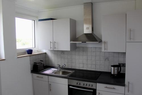 威克贝格Fewo Weitsicht的厨房配有白色橱柜、水槽和窗户。
