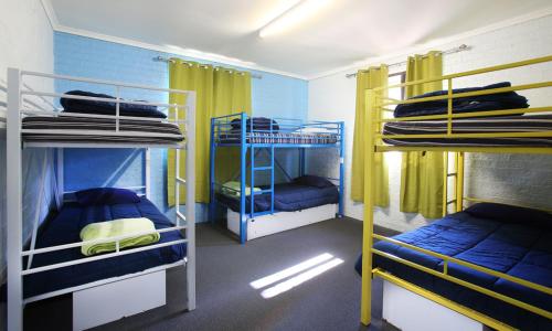 科夫斯港奥斯特尔背包客旅舍的客房设有三张双层床,拥有蓝色的墙壁和黄色的窗帘