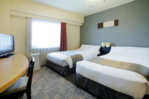 札幌札幌东急REI酒店的酒店客房设有两张床、一张桌子和一台电视。