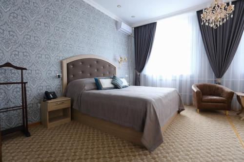 EkibastuzHotel Bahetle的一间卧室配有一张床、一把椅子和一个吊灯。