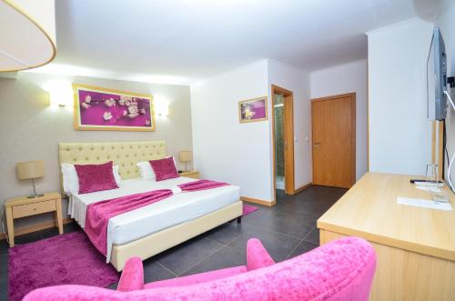 普拉亚Vivi Hotel的一间卧室配有一张床和两张粉红色的椅子