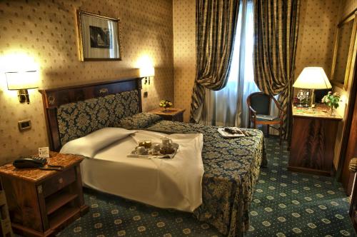 罗马西里西亚酒店的酒店客房设有一张大床和一张桌子。