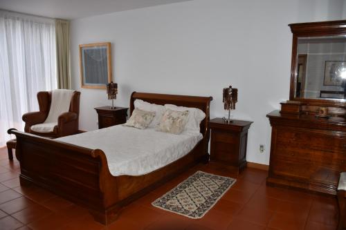 卡罗拉Caloura Camellia House的一间卧室配有一张木床和一把椅子