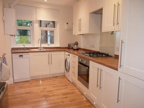 布罗肯赫斯特Brockenhurst Apartments的厨房铺有木地板,配有白色橱柜。