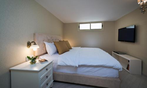 埃拉特Noa's Place的卧室配有白色的床和电视。