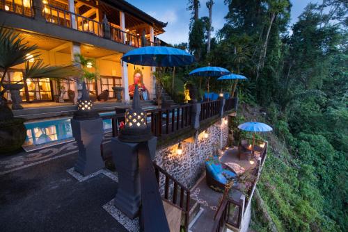 乌布Villa Kalisat Resort的一座带游泳池、遮阳伞和椅子的房子