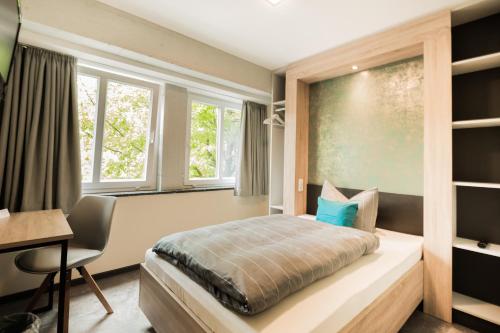 埃姆登Hotel DH -Deutsches Haus-的卧室配有一张床、一张书桌和窗户。