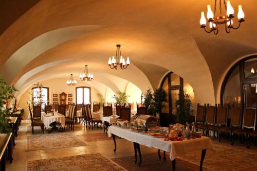 阿尔巴尤利亚中世纪酒店的大型用餐室配有桌椅和吊灯。