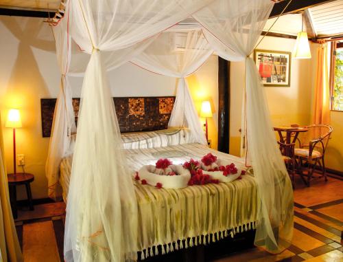 因巴塞Vilangelim Eco-Pousada的一间卧室配有带鲜花的天蓬床