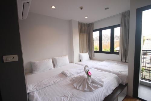 曼谷达林旅舍的卧室配有白色的床,床上有花