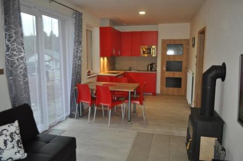 伏尔塔瓦河畔利普诺Moderni Domek Lipno的厨房配有红色橱柜和桌椅