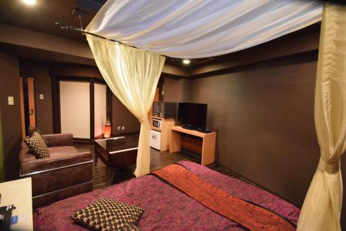 横滨H-7努达酒店（仅限成人）的一间卧室配有天蓬床和沙发