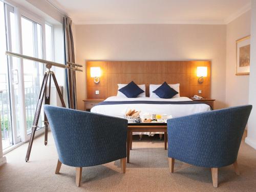 浦耳海峰酒店的酒店客房,配有一张床和两把椅子