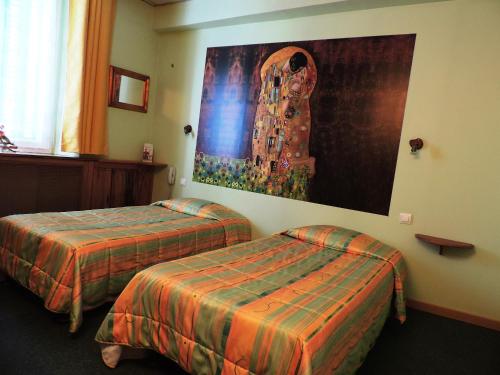 迪涅莱班Hotel De Provence的酒店客房设有两张床,墙上挂有绘画作品