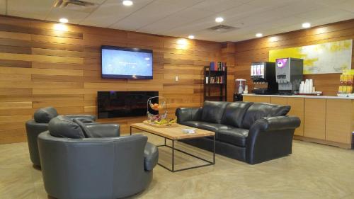 WabascaWabasca Inn的一间设有两张真皮座椅和平面电视的等候室
