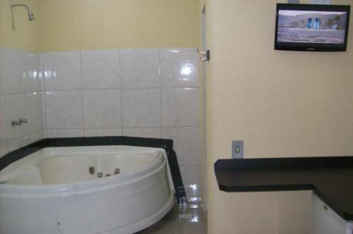索罗卡巴Hotel Pousada Village的带浴缸的浴室和墙上的电视