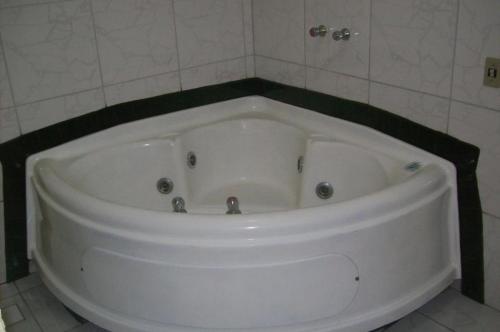 索罗卡巴Hotel Pousada Village的浴室内设有大型白色浴缸。