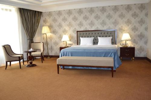 奎兹洛达Sultan Plaza hotel的一间卧室配有一张床、两把椅子和两盏灯。